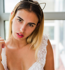 Beautiful young woman posing near window wearing lingerie