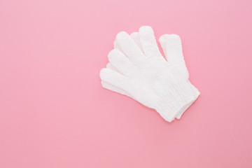 Woman exfoliating massage glove for shower on pink background.Gloves for use in the shower for massage and scrub. Beauty background with cosmetic products. Beauty, health and spa concept