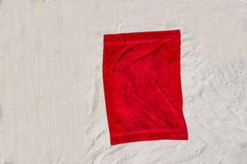Red towel on a sandy beach on a sunny summer day.