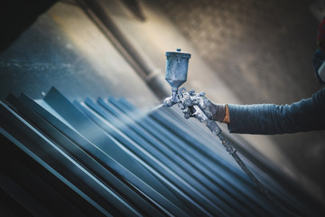 Man painting metal products with a spray gun - obrazy, fototapety, plakaty