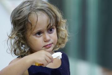 Three-year-old girl eating ice cream during her holidays in Lefkas
