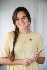 beautiful young brunette woman with braid and bunch of brushes in her hands