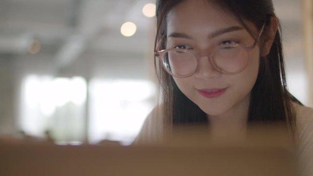 Freelance Asian women working on laptop at office. Young Asia business Girl using the computer for trade, send email, digital work on the internet on table at workplace concept. Slow motion.