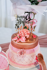 happy 70th birthday mom in rose gold on birthday cake with shoe and handbag fresh flowers