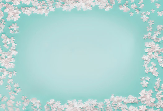 Lovely frame of little white flowers on turquoise blue background, top view, copy space. Flat lay