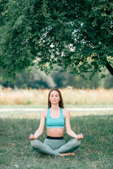 Fototapeta na wymiar Brunette fitness girl doing yoga outdoor.