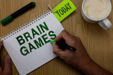 Conceptual hand writing showing Brain Games. Business photo showcasing psychological tactic to manipulate or intimidate with opponent Man holding marker notebook reminder wooden table cup coffee