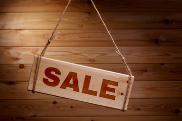 Wooden signboard with the words SALE on a rough rope on a beautiful wooden background