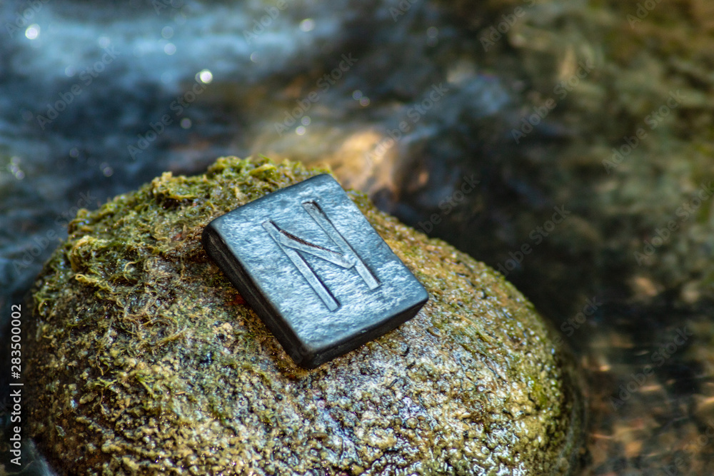 Poster norse rune hagalaz (hagal) on the stone and the evening river background. excitement, shake, exit th