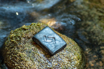 Norse rune Yera on the stone and the evening river background.  Harvest, cycle, karma. Hard work to achieve the result.