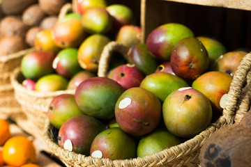 Naklejka na ściany i meble ripe juicy mango in wicker baskets on market counter