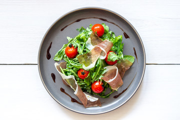 Salad with arugula, tomatoes and prosciutto. Italian cuisine. Healthy eating. Diet.