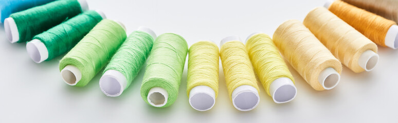 panoramic shot of bright and colorful threads on white background