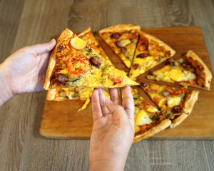  A girl in a fast-food restaurant picks up a piece of pizza in front of a table with the rest of...