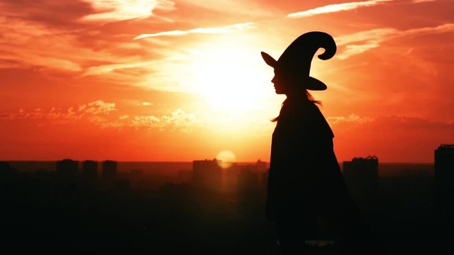 silhouette hag in hat holding magic apple posing outdoor slow motion view on sky at sunrise