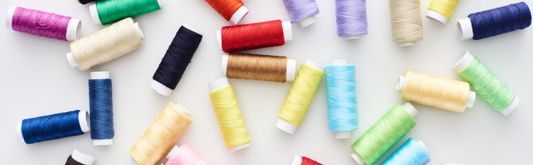 panoramic shot of bright and colorful threads on white background