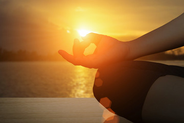 Young women meditate while doing yoga meditation, spiritual mental health practice with silhouette of lotus pose having peaceful mind relaxation on beach outdoor with sunset golden heavenly.