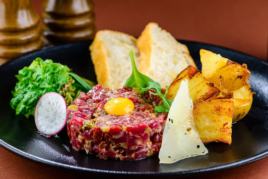 Close up of beef tartar with capers and small toasts.