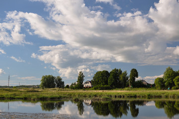 A rural landscape in the European part of Russia on a sunny day with a house and a river
