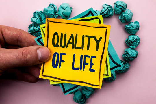 Handwriting Text Quality Of Life. Concept Meaning Good Lifestyle Happiness Enjoyable Moments Well-being Written Sticky Note Paper Holding By Man Plain Background Heart Paper Balls.