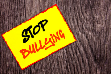 Conceptual hand writing text showing Stop Bullying. Concept meaning Awareness Problem About Violence Abuse Bully Problem written Yellow Sticky Note Paper the wooden background.