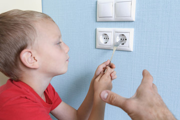 A father is trying to stop a child reaching for an electrical outlet. Electric shock hazard concept...