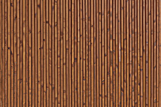Background of the boards facing the wall. The texture of the wooden surface of the boards. Smooth dark brown planks with knots.