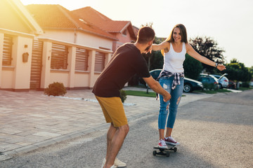 fancy happy couple driving skateboard outdoor