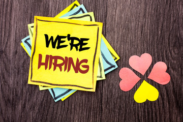 Text sign showing We're Hiring. Conceptual photo Recruiting Hiring Now Recruitment Vacancy Announced Hire written Stacked Sticky Note Papers the wooden background Hearts next to it.