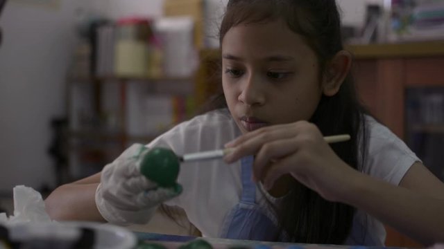 Asian cute girl is making crafts from egg shells on the desk, Young girl is coloring egg shells at home for her homework, Education concept.
