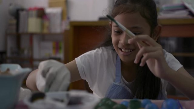 Asian cute girl is making crafts from egg shells on the desk, Young girl is coloring egg shells at home for her homework, Education concept.