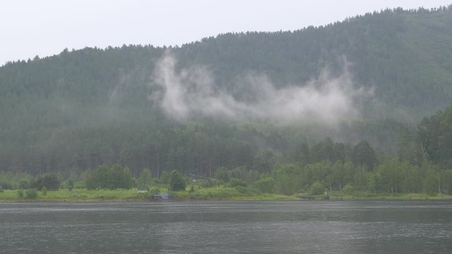 In cloudy weather on the banks of the Yenisei river it rains