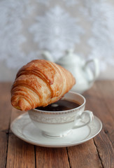 Croissant and a Cup of tea coffee on a wooden table