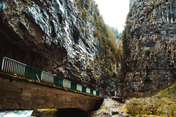 Bridge over the mountain river. Stone bag Abkhazia in spring. Canyon road surrounded by rocks.Trees grow on a ridge. Cliffy hills above the road. Unusual place in mountainous areas.