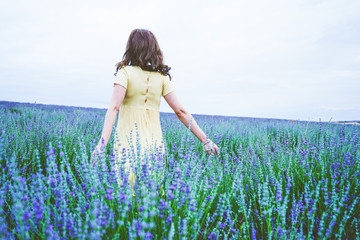Fototapeta na wymiar Back view of a young woman in a field of lavender