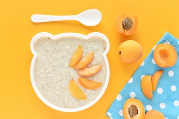 Oatmeal porridge with fresh apricot, healthy eating, kids meal, funny bear shape plate, top view.