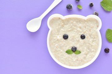 Healthy oatmeal porridge with blueberries for kids, plate in shape of bear, fun food.