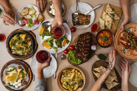 Wide And Tasty Table Covered With Delicious Ukrainian Cuisine On Which Sits A Large Family Or Friends Their Hands At The Table During Meals