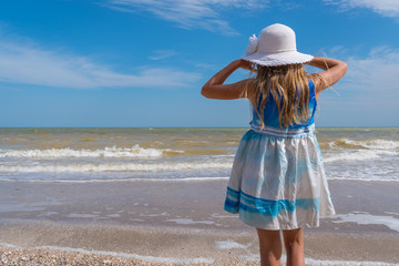 Girl in white hat on sea beach over blue sky background