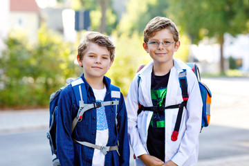 Two little kid boys with backpack or satchel. Schoolkids on the way to school. Healthy adorable...