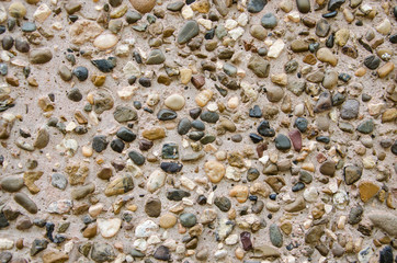  The abstract background. Many multi-colored small stones on the sand of the river.