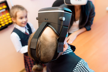child with vr virtual reality goggles in classroom. Multiethnic pupil having fun with virtual reality headset at elementary school. Happy boy gesturing while using VR headset in classroom.