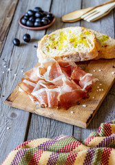 Prosciutto ham and bread on a wooden background. Italian cuisine. Rustic style.