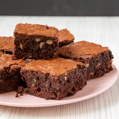 Homemade chocolate brownies on a pink plate, side view. Close-up.