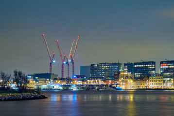 Fototapeta na wymiar Tall cranes and modern buildings in Amsterdam at night.