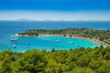 Fototapeta na wymiar Panoramic view on Kosirina beach lagoon on Murter island in Croatia, anchored sailing boats and yachts on blue sea