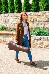 Young girl in coat with case for violin in hand