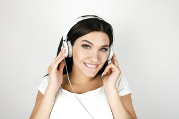 brunette young woman listening her favourite songs in headphones feeling happy on isolated white background