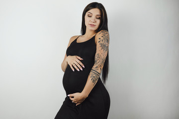 brunette young pregnant beautiful woman in long black trendy dress her belly on isolated white background