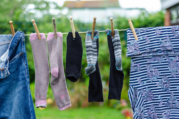 Socks hanging on a clothes line in a garden to dry.